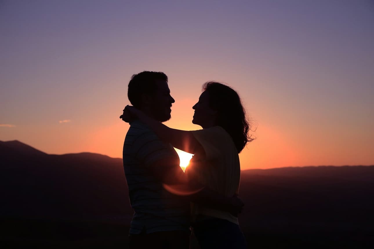The couple silhouetted against a warm sunset